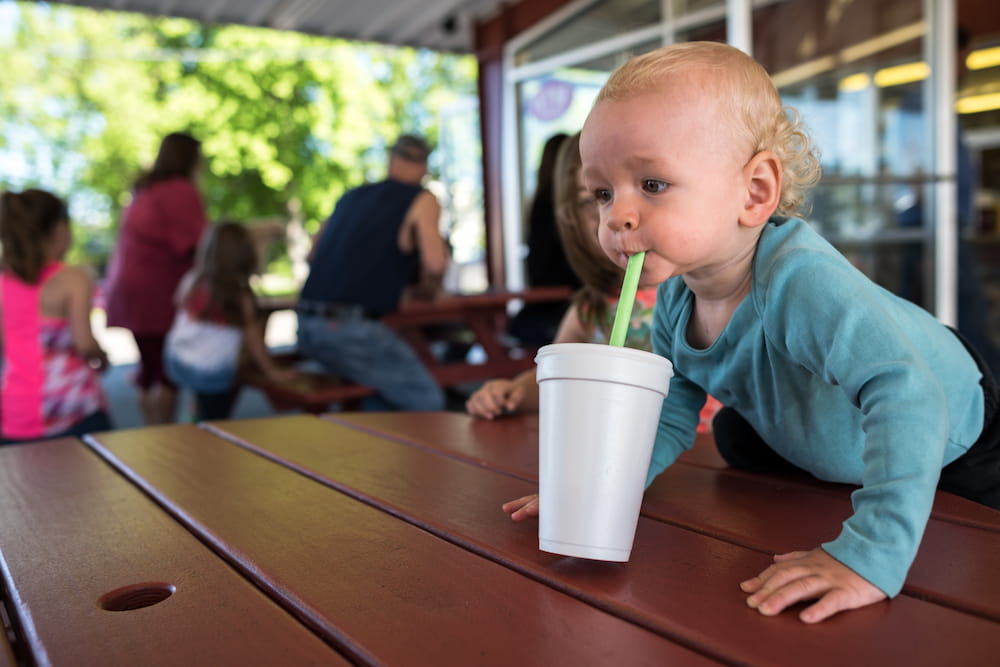 Toddler drinks from a straw in a foam cup