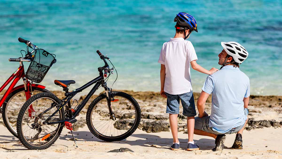 Father and son kneel beside bicycles beside a lake