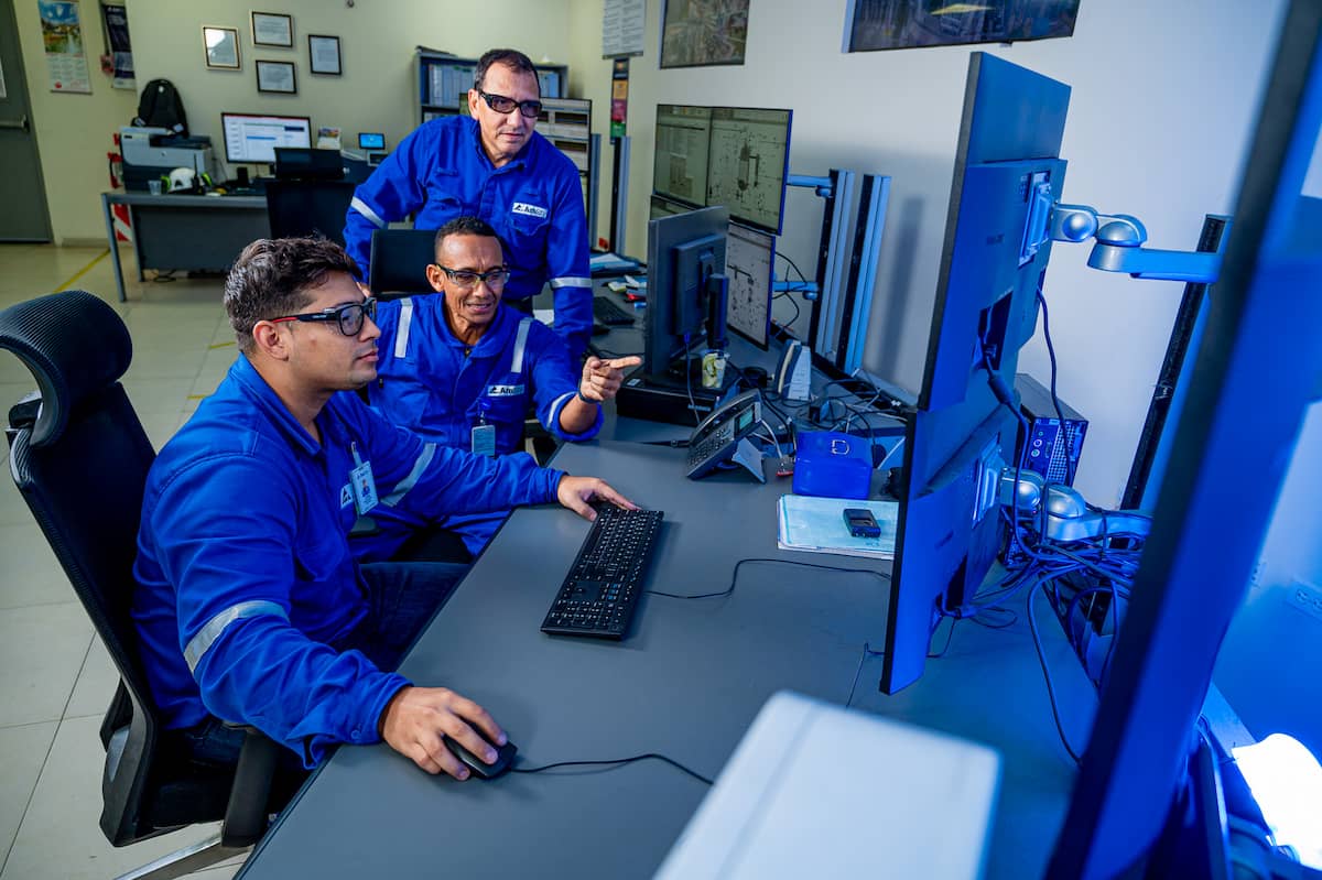 A group of employees study a computer screen